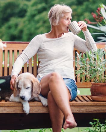 Older woman sitting on bench drinking coffee